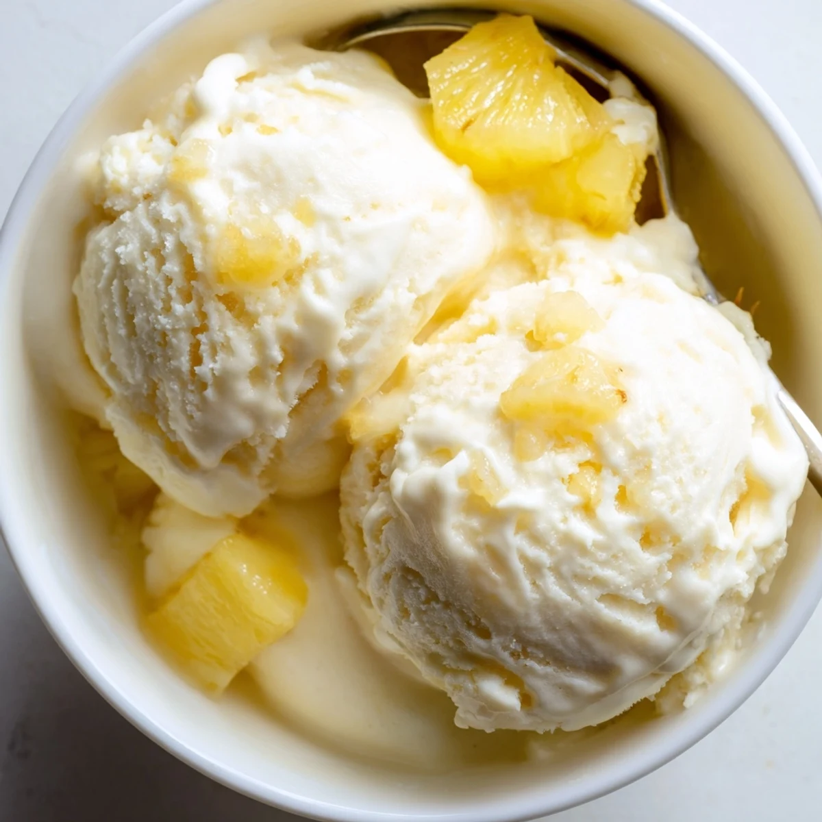 A scoop of Creamy Pineapple Ice Cream glistening, tropical aroma, soft texture