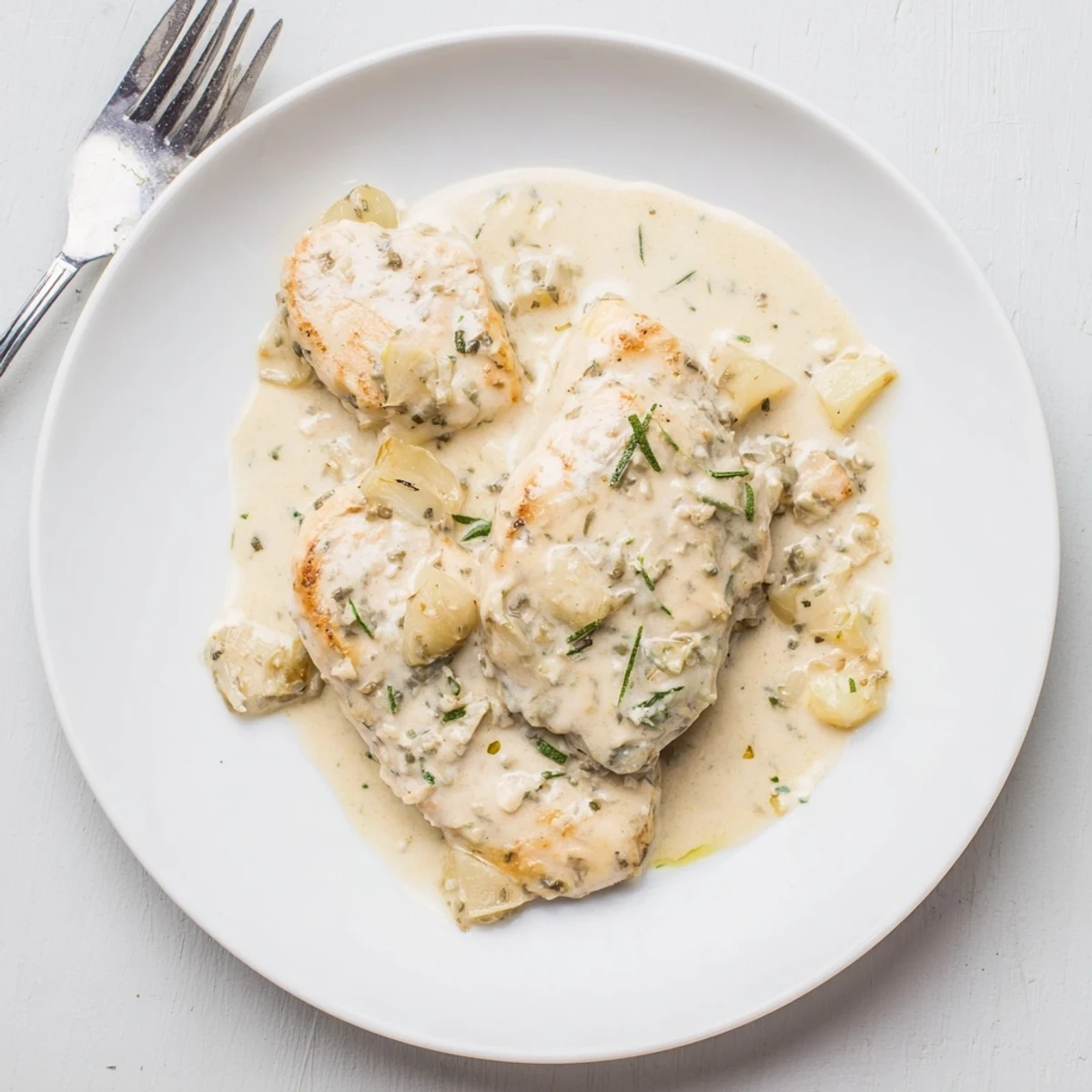 Golden chicken breasts swimming in a luscious creamy herb sauce flecked with fresh parsley and chives