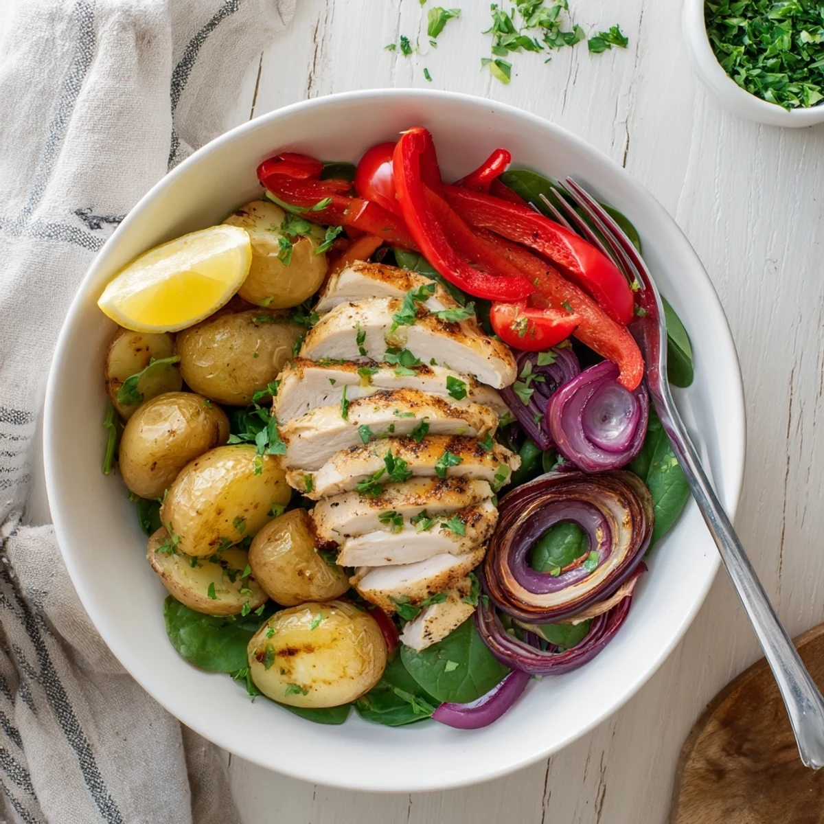 Golden roasted baby potatoes and juicy grilled chicken atop fresh spinach in a skinny chicken and roasted potato bowl