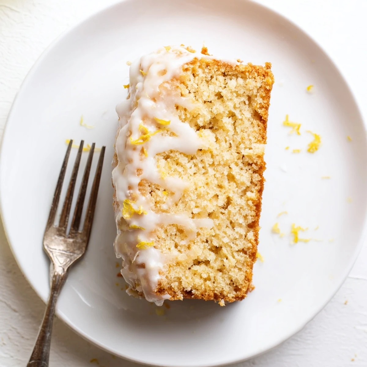 Moist slice of Greek yogurt lemon loaf showing tender crumb texture on a white plate