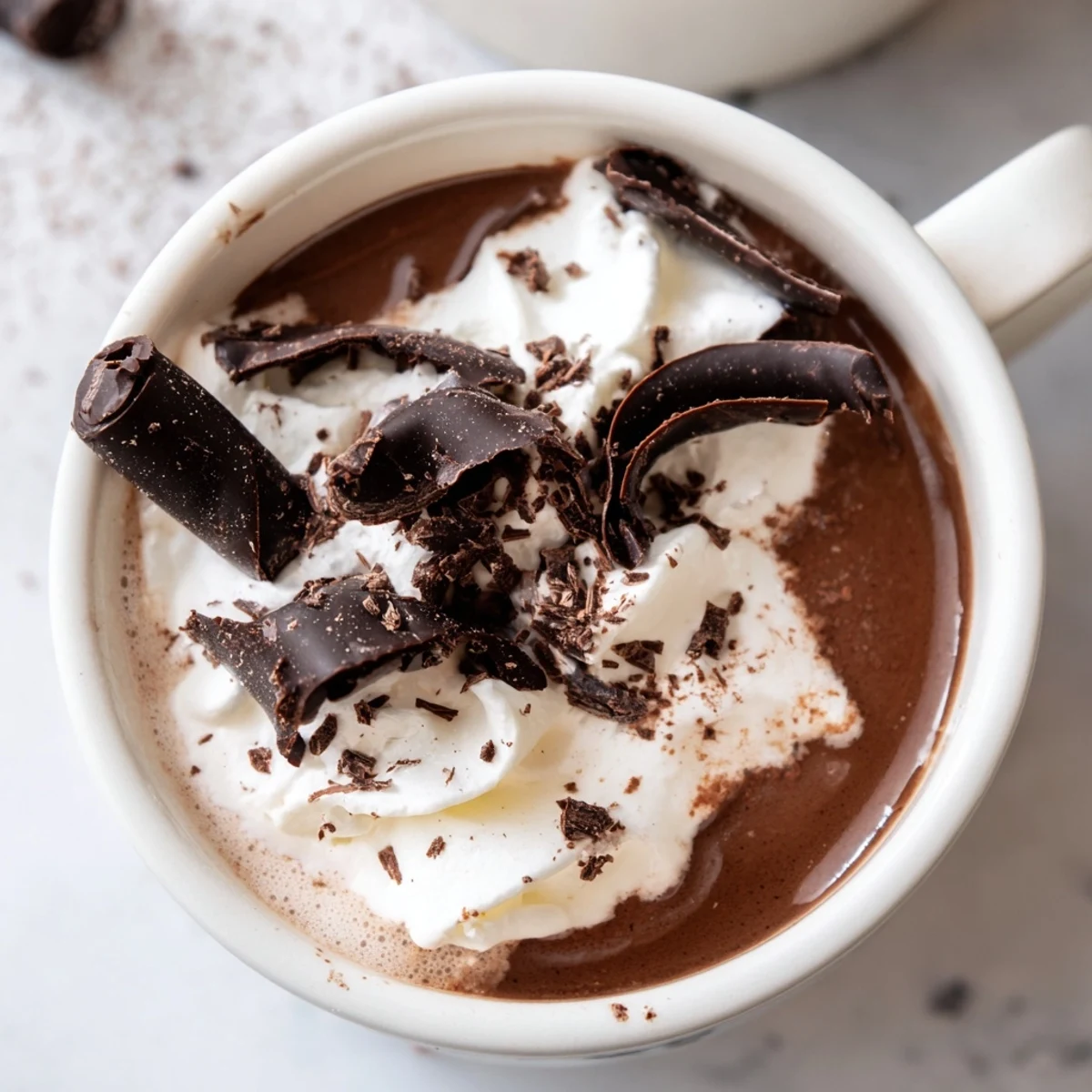 Steaming mug of sugar-free keto hot chocolate drizzled with sugar-free whipped cream