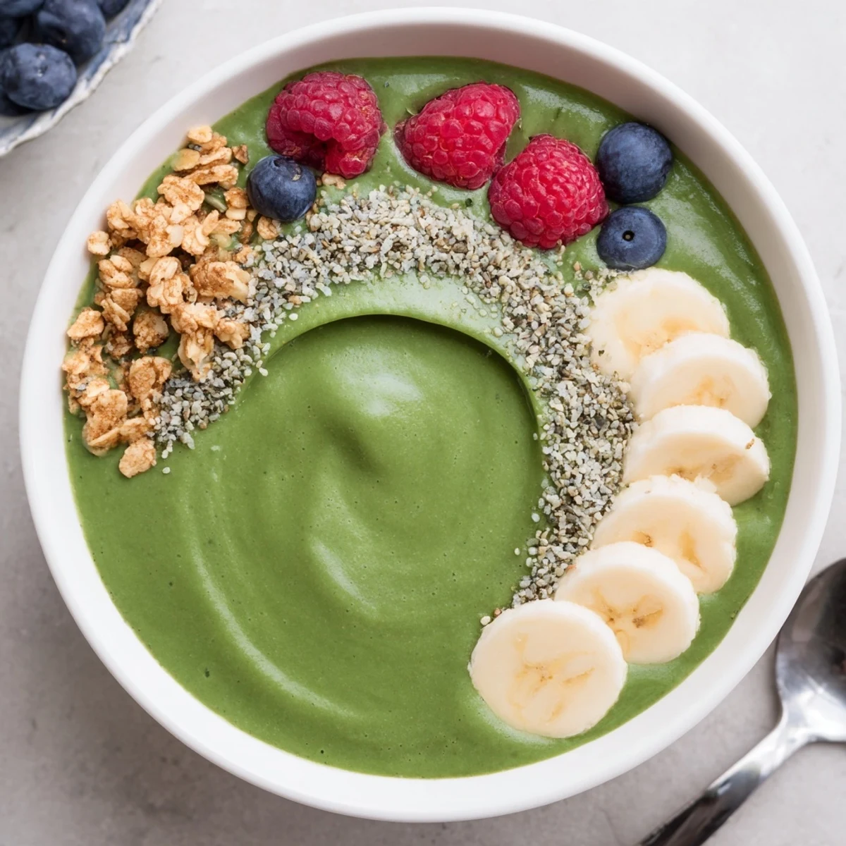 Green Smoothie Bowl With Spirulina, Banana & Hemp Seeds garnished with fresh berries