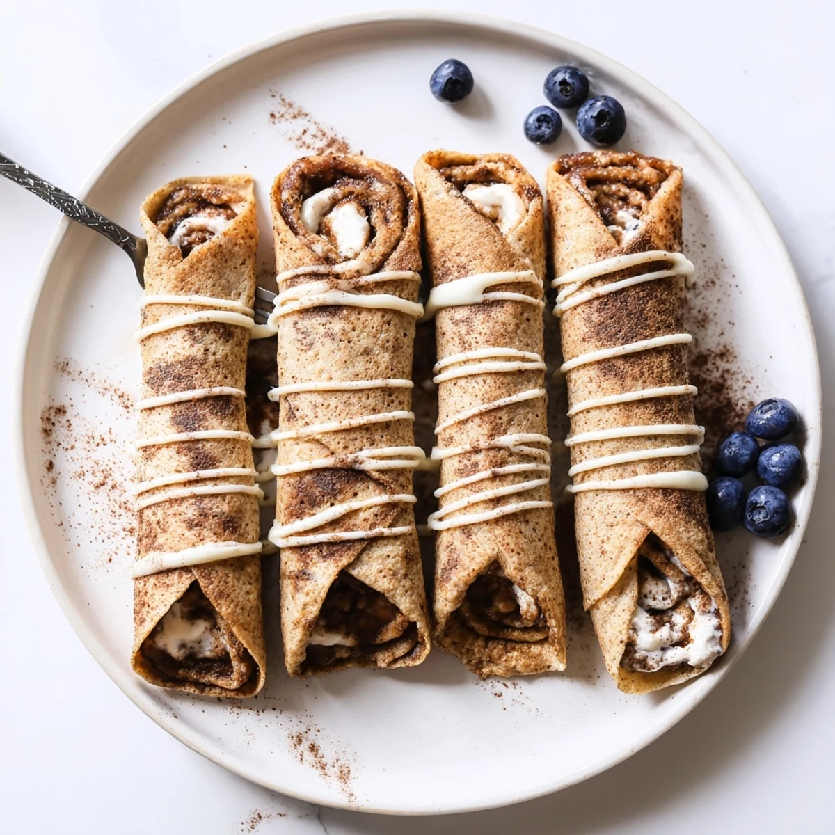 Pan-seared Cinnamon Roll Protein Crepes filled with creamy cinnamon spread, served warm