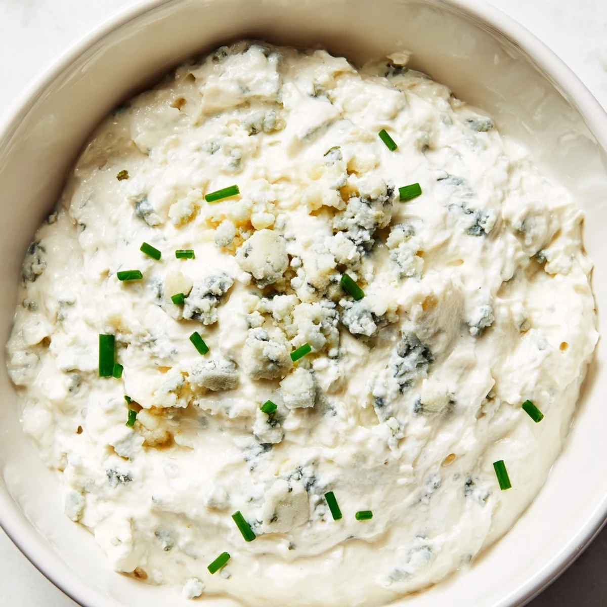 Creamy blue cheese dip served in a bowl with fresh celery and carrot sticks