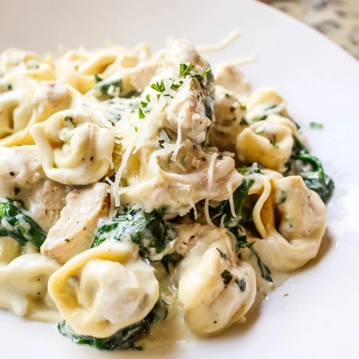 Golden seared chicken and cheese tortellini tossed with fresh spinach in creamy garlic sauce