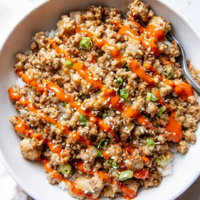 Colorful crisp vegetables topping Ground Turkey Rice Bowls with Bang Bang Sauce in white bowls