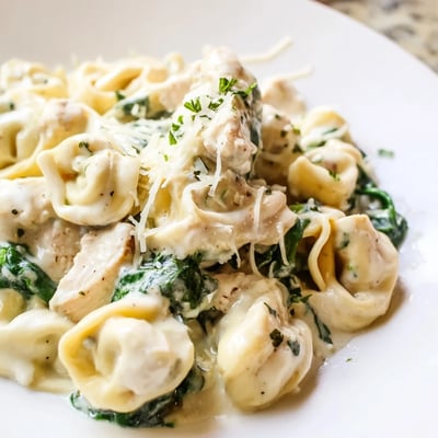 Golden seared chicken and cheese tortellini tossed with fresh spinach in creamy garlic sauce